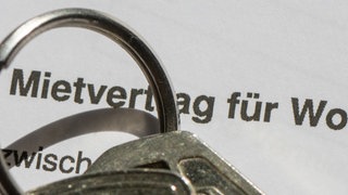 Ein Wohnungsschlüssel liegt auf einem Mietvertrag für eine Wohnung.