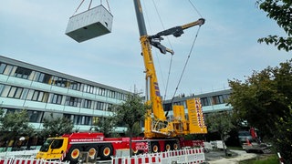 Das erste Modul wird mit dem Schwerlastkran auf die Kinderklinik gesetzt: Die Bethesda-Schule im SLK-Klinikum bekommt einen Neubau. Dort werden Kinder bei längeren Krankenhausaufenthalten unterrichtet.