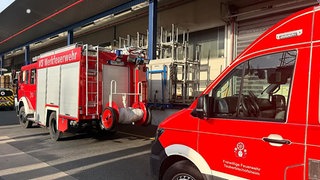 Zwei Feuerwehrautos vor einer Firma. Bei einem Arbeitsunfall in Tauberbischofsheim wurde ein Mann lebensgefährlich verletzt. Er wurde in einem Hochregallager eingeklemmt.
