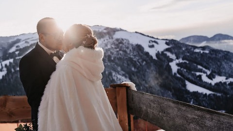 Hochzeit im Schnee: Ein Paar küsst sich in den Bergen (Symbolbild). Heiraten zu Jahresende kann auch richtig schön sein. 