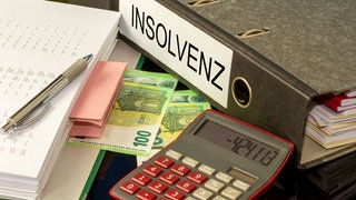 Symbolbild Insolvenz: Ordner, Taschenrechner und Banknoten: HRZ Wohnmobile aus Bretzfeld sind insolvent.