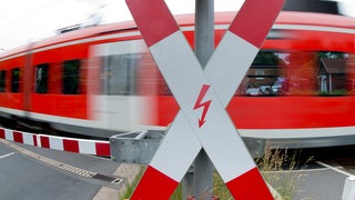 Ein Zug passiert einen Bahnübergang mit einem Andreaskreuz 