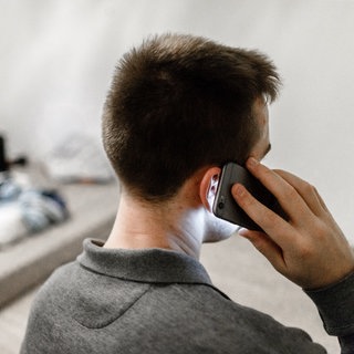 Ein Mann ruft mit seinem Handy bei der Telefonseelsorge an. Viele Menschen sind in der Weihnachtszeit alles andere als glücklich. Deshalb laufen die Leitungen der Telefonseelsorge an den Weihnachtsfeiertagen heiß. 