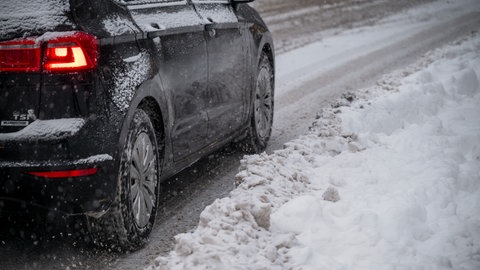 Ein Auto fährt auf einer verschneiten Straße (Symbolbild). Vor allem im Main-Tauber-Kreis ist es wegen Schneefalls am Donnerstagmorgen zu mehreren Unfällen gekommen.