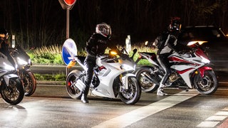 Motorräder an einer Kreuzung bei Nacht (Symbolbild). Ein Motorradfahrer hat sich am Wochenende eine wilde Verfolgungsjagd mit der Polizei geliefert. Er ist entkommen.