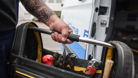Ein Handwerker stellt eine Tasche mit Werkzeug in sein Fahrzeug (Symbolbild). In Heilbronn häufen sich derzeit Einbrüchte in Handwerkerautos. Die Polizei vermutet eine Serie. 