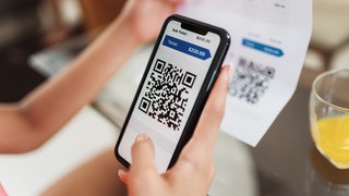 Eine Person scannt mit ihrem Handy einen QR-Code ab (Symbol): In Tauberbischofsheim sind gefälschte Bankschreiben aufgetaucht mit QR-Codes, die auf gefälschte Internetseiten führen.