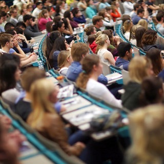 Studenten sitzen in einem Hörsaal (Symbolbild). Gerade zum Semesterstart ist in vielen Städten günstiger Wohnraum rar.