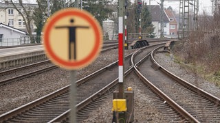 Im Vordergrund ein unscharf dargestelltes Betreten-Verboten-Schild, im Hintergrund scharf dargestellt mehrere Bahngleise. (Symbolbild) Weil drei Kinder in Öhringen (Hohenlohekreis) unerlaubt die Gleise überquert haben, musste eine Straßenbahn eine Schnellbremsung einlegen. Die Bundespolizei warnt: Das ist lebensgefährlich.