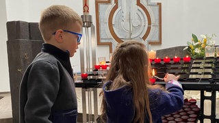 Kinder zünden in einer Kiche eine Kerze an (Symbolbild). 