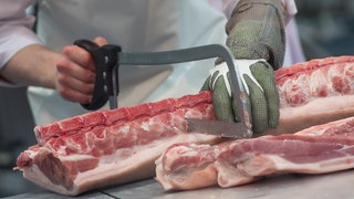 Eine Person zerlegt ein Stück Fleisch (Symbolbild): Das Unternehmen Boeser Frischfleisch kauft den Schlachthof Crailsheim