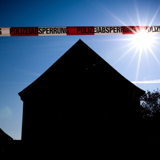 Ein Absperrband vor Häusern bei Nacht (Symbolbild). Die Staatsanwaltschaft hat den mutmaßlicher Mörder von Schöntal angeklagt. Er soll seine Schwiegermutter getötet haben. 