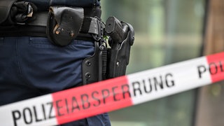 Polizist hinter einer Absperrung (Symbolbild). In Crailsheim hat ein Mann mehrere Schüsse abgegeben. Dann stellte sich heraus, es war eine Schreckschusswaffe.