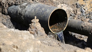 Wasser läuft aus einem Rohr (Symbolbild). In Bühlertann kann ein Wasserrohrbruch nicht repariert werden, weil es einen Streit zwischen Nachbarn und der Gemeinde gibt.