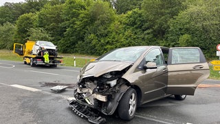 Ein braunes Auto mit stark eingedrücktem Motorraum. AUf der Straße schimmert hellbraun eine verschmierte Flüssigkeit.
