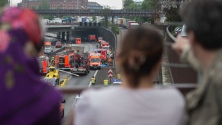 Schaulustige stehen auf einer Brücke und beobachten einen Unfall (Symbolbild). 