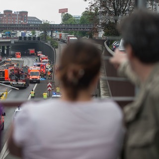 Schaulustige stehen auf einer Brücke und beobachten einen Unfall (Symbolbild). 
