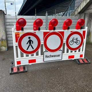 Ein Schild warnt am Rhein vor Hochwasser.