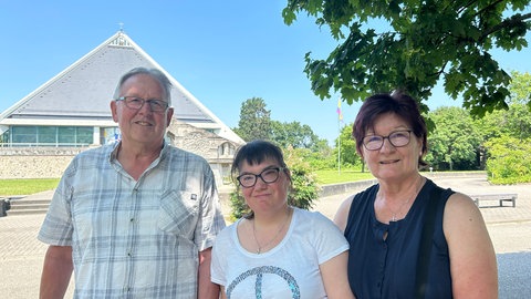 Eine Familie steht vor der Autobahnkirche in Baden-Baden. Die Kirche steht auf einem Rasthof für Reisende der A5.