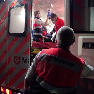 Ein Patient mit Herzstillstand wird eingeliefert. Er liegt im Rettungswagen - Ersthelfer um ihn herum. 