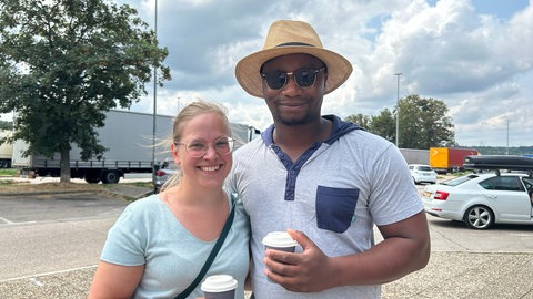 Ein Paar steht auf dem Parkplatz einer Raststätte bei Pforzheim. Sie brauchen eine Pause vom Stau.