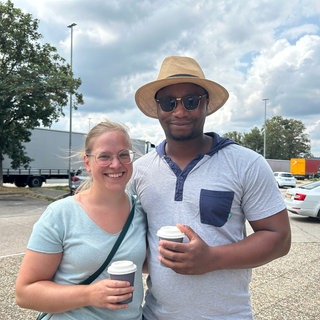 Ein Paar steht auf dem Parkplatz einer Raststätte bei Pforzheim. Sie brauchen eine Pause vom Stau.