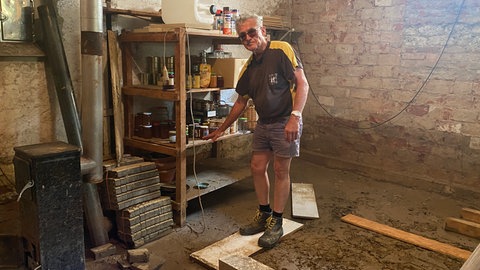 Mann vor Kelleregal, auf schlammigem Boden - Rolf Hentz hat seinen vollgelaufenen Keller in Gondelsheim endlich ausgepumpt.