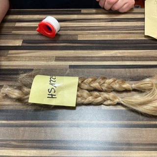 Die Zöpfe von Emil aus Rastatt liegen auf einem Tisch. Sie sind beschriftet und werden nun zur Perücke