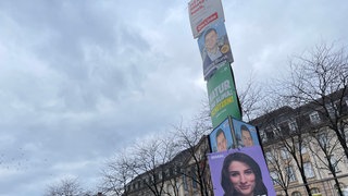Mehrer Wahlplakate von verschiedenen Parteien hängen an einer Laterne