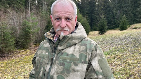 Klaus Kary steht auf einer Wiese vor einem Waldstück im Schwarzwald.
