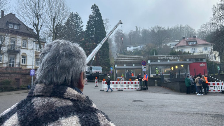 Ein Mann ist von hinten zu sehen. Er beobachtet den Abbau der Turmbergbahn in Karlsruhe-Durlach.