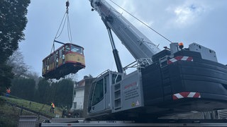 Abbau der Turmbergbahn: Ein Kran hebt den ersten Wagen der Turmbergbahn in Karlsruhe von den Schienen. 