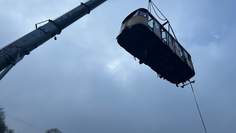 Ein Kran hebt den ersten Wagen der Turmbergbahn in Karlsruhe von den Schienen. 