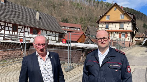 Feuerwehrmann Johannes Warth (re.) und Ortsvorsteher Guido Wieland vor dem Brandhaus