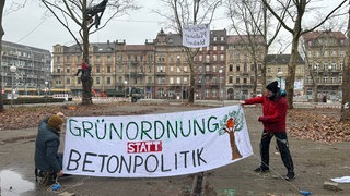 Die Protestierenden haben Forderungen auf Laken geschrieben, die sie in die Platanen vor dem Badischen Staatstheater in Karlsruhe hängen. 