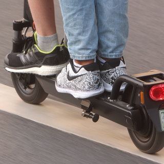 Symbolfoto E-Scooter-Unfall: Zwei Personen fahren auf einem E-Scooter