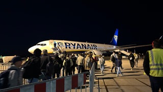 Viel Betrieb am Flughafen KarlsruheBaden-Baden. Sicherheitskontrollen und Boarding funktionierten. Menschen steigen in ein Flugzeug auf dem Rollfeld.