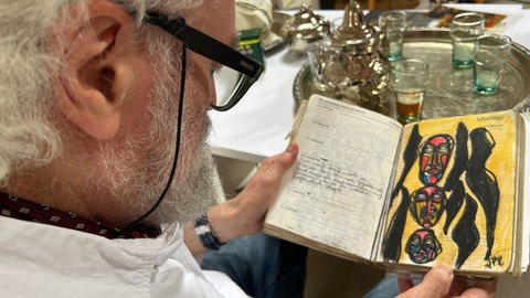 Künstler Jörg Mohme aus malsch schaut in sein Notizbuch.