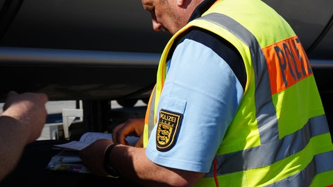 Ein Polizist schlägt bei der Gefahrgutkontrolle auf der A8 bei Pforzheim Informationen in einem Gesetzesbuch nach.