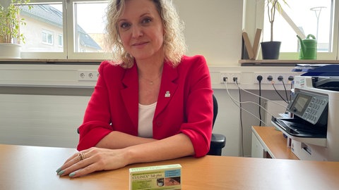 Bürgermeisterin Veronika Laukart sitzt an einem Schreibtisch, vor ihr liegt eine Packung mit BTI-Tabletten.