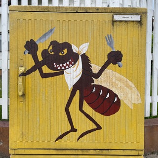 Eine gemalte gefräßige Stechmücke mit Besteck ist auf einem Stromverteilerkasten abgebildet.