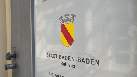 Eine Tür im Rathaus mit dem Wappen der Stadt Baden-Baden. Der Gemeinderat der Stadt hat die Abstimmung zu den Sparmaßnahmen vertagt.