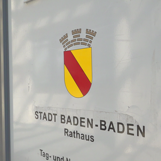 Eine Tür im Rathaus mit dem Wappen der Stadt Baden-Baden. Der Gemeinderat der Stadt hat die Abstimmung zu den Sparmaßnahmen vertagt.