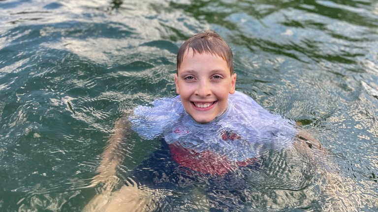 Ein Junge schwimmt im Altrhein bei Philippsburg.