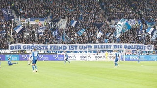 Einige KSC-Fans halten ein Spruchband in die Höhe.