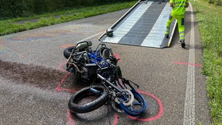 Ein zertrümmertes Motorrad liegt auf einer Straße.