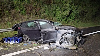 Ein demoliertes schwarzes Auto auf der A8 bei Pforzheim. Der Wagen hat sich mehrfach überschlagen und Feuer gefangen - Ersthelfer griffen schnell ein und retteten wohl Menschenleben.