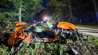 Bei einem Unfall bei Neumalsch (Kreis Karlsruhe) ist am Donnerstag ein Mann schwer verletzt worden, weil er mit seinem Auto gegen einen Baum geprallt war. Das orange-farbene, stark zerstörte Auto ist hier neben der Fahrbahn zu sehen.