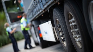 (Symbolbild) Lkw mit Anhänger wird von Polizisten kontrolliert. Bei Baden-Baden wurde ein Anhänger samt Ladung gestohlen.