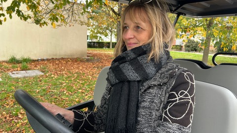 Simone Maria Dietz sitzt am Steuer des Golfmobils. Der Wagen ist auf dem Hauptfriedhof Karlsruhe für den Transport von Besuchern an Allerheilgen im Einsatz.